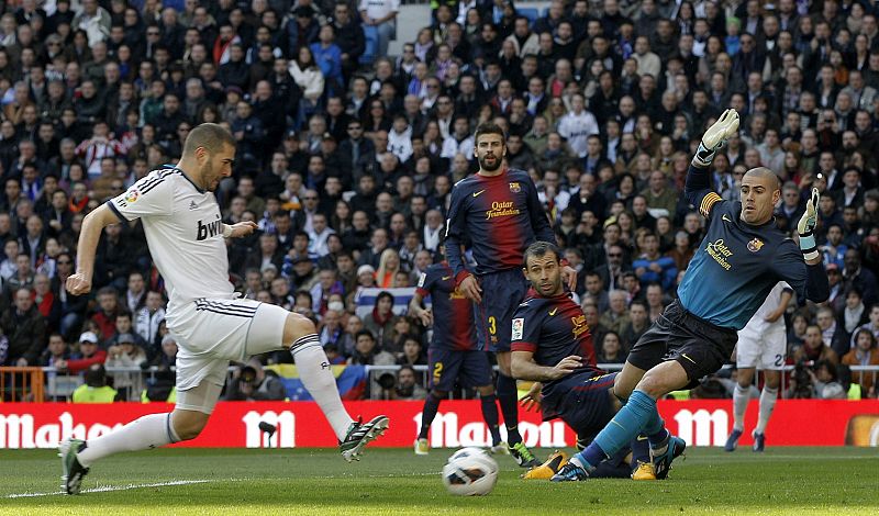 El delantero francés del Real Madrid Karim Benzema (i) supera al portero del Barcelona Víctor Valdés y consigue el primer gol de su equipo.