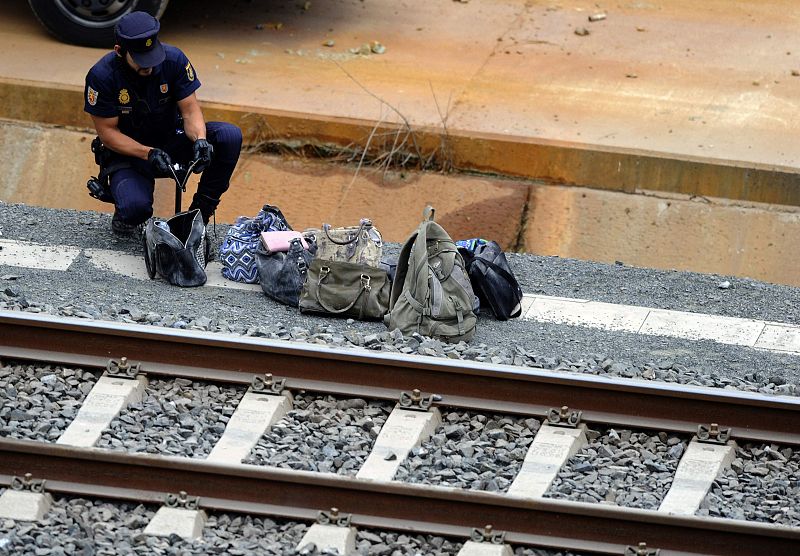 Un oficial de policía revisa las pertenencias personales para identificar a los pasajeros del tren siniestrado.