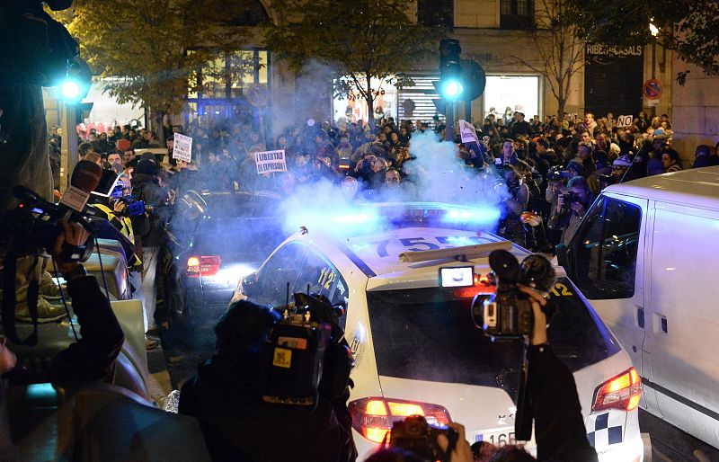 Un grupo de manifestantes rodea un coche policial durante las protestas posteriores a la movilización "Rodea el Congreso"