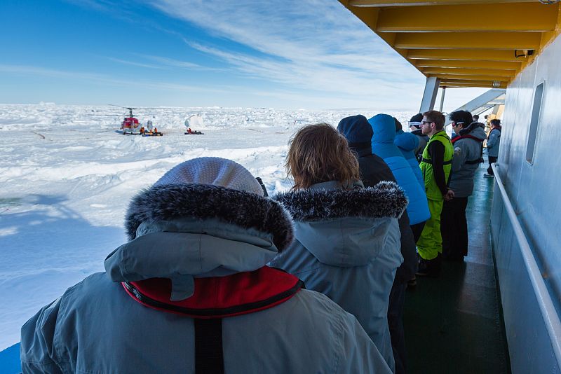 Científicos y turistas componían el pasaje del Akademik Shokalskiy. En la imagen, observan al helicóptero que les evacuará.