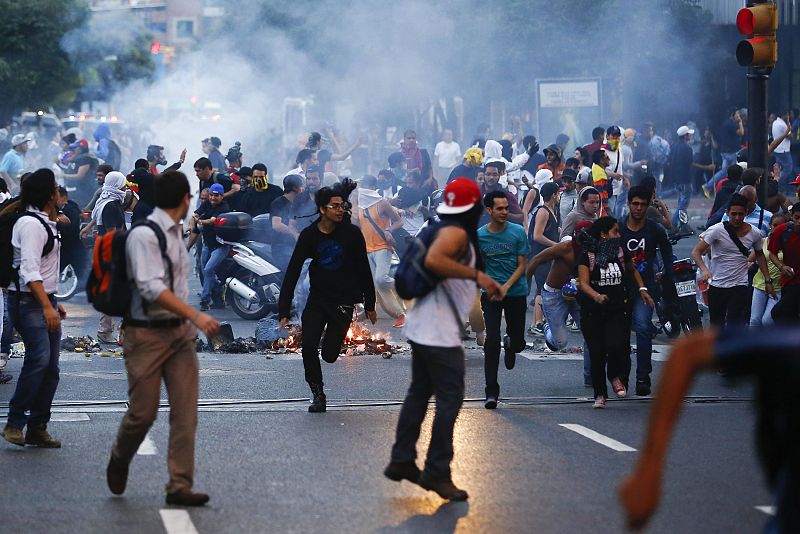 Manifestantes huyen del gas lacrimógeno durante la jornada de protestas en Caracas.