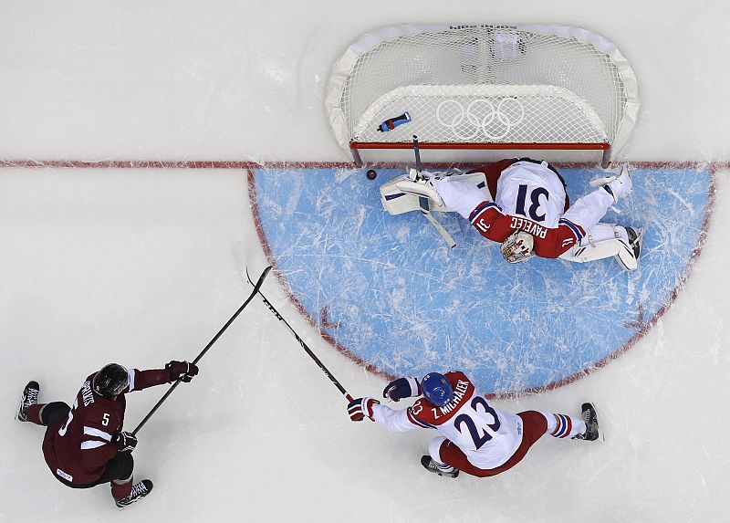 Latvia's Sprukts scores on goalie Pavelec of the Czech Republic as Michalek of the Czech Republic defends during the first period of their men's preliminary round ice hockey game at the Sochi 2014 Winter Olympic Games