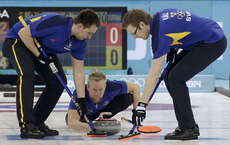 Sweden's skip Niklas Edin delivers a stone as second Fredrik Lindberg and lead Viktor Kjaell prepare to sweep during their men's curling round robin game against Russia in the Ice Cube Curling Centre at the Sochi 2014 Winter Olympic Games