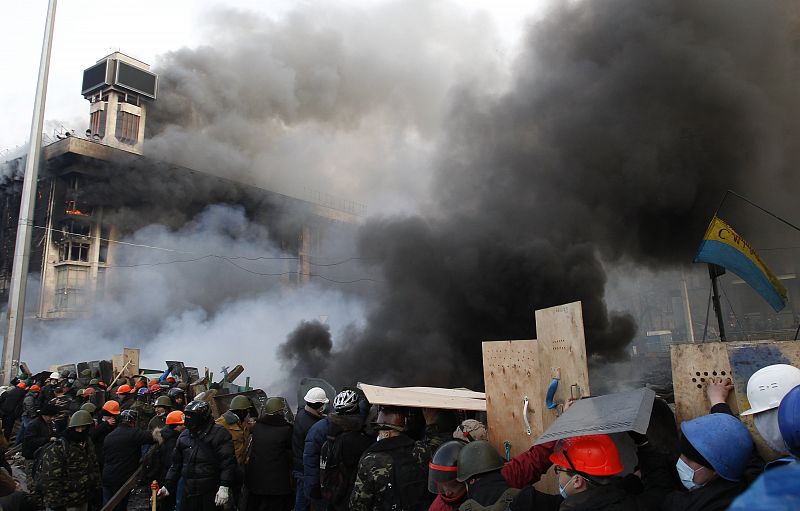 Barricada de los opositores en la plaza, con el edificio de los sindicatos incendiado al fondo