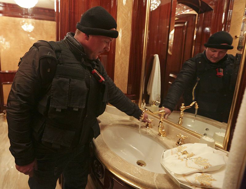 A man turns on a water tap inside the residence as anti-government protesters and journalists walk on the grounds of the Mezhyhirya residence of Ukraine's President Viktor Yanukovich in the village Novi Petrivtsi outside Kiev