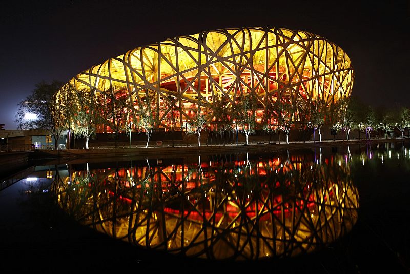 National Stadium, also known as "Bird's Nest", is seen reflected in a lake before Earth Hour at Olympic Park in Beijing
