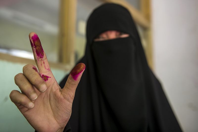 Una mujer egipcia oculta por un velo muestra sus dedos entintados tras emitir su voto