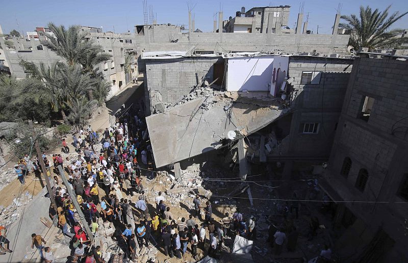 Palestinians gather around a house which police said was destroyed in Israeli air strikes in Khan Younis in the southern Gaza Strip