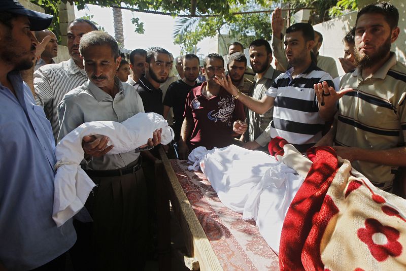 El padre de un niño palestino fallecido durante los ataques israelíes sostiene su cuerpo durante el funeral