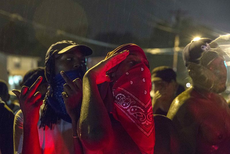 Protesters gesture as they stand in a street in defiance of a midnight curfew in Ferguson