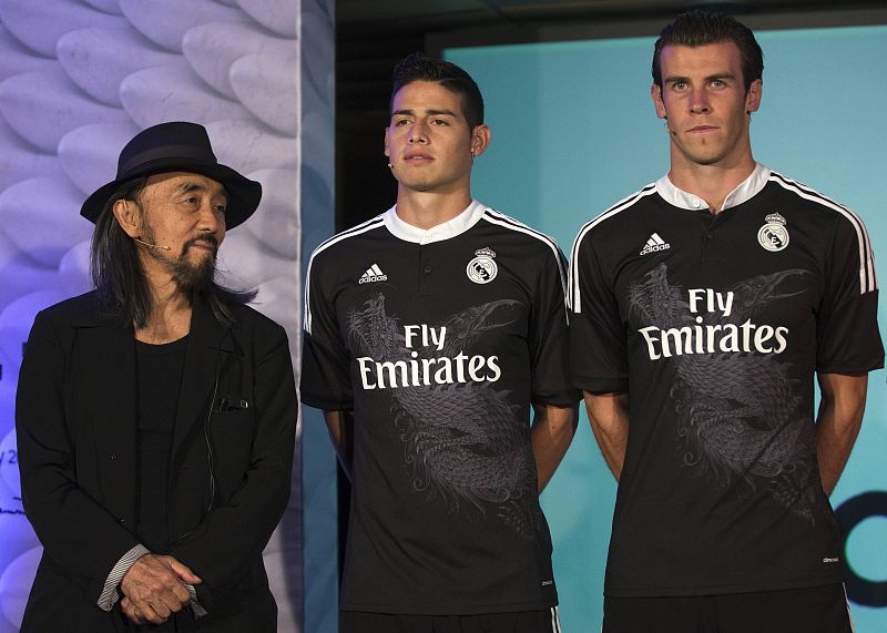 Gareth Bale (d) y James Rodríguez posan delante de los fotógrafos con el diseñador japonés Yohji Yamamoto (i).
