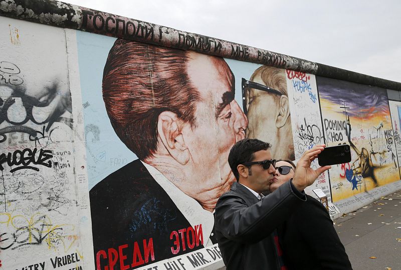 Dos turistas se fotografían en un fragmento de la famosa East Side Gallery, en Berlín.