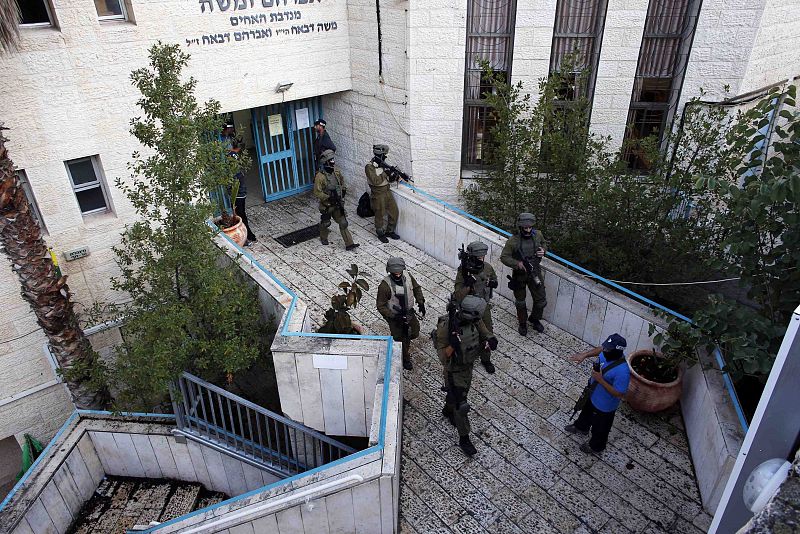 Soldados israelíes registran la sinagoga donde se ha producido el ataque, en el barrio de Har Nof