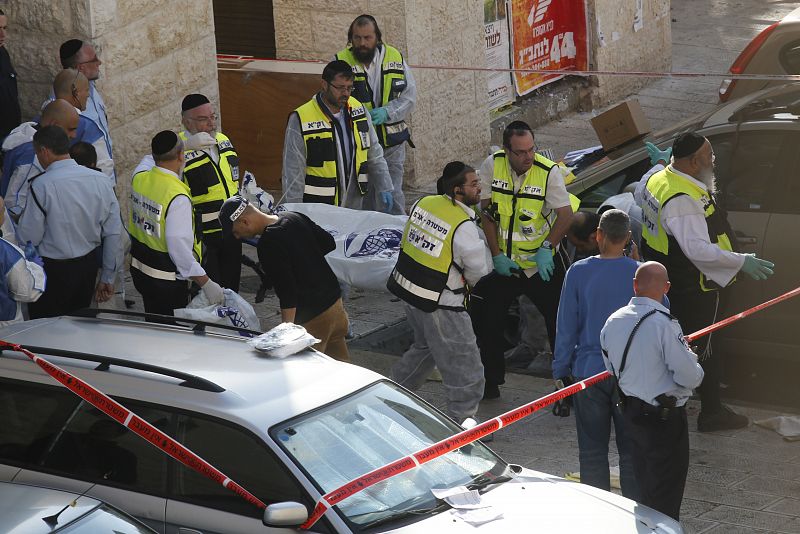 Voluntarios de los servicios de emergencia israelíes transportan el cuerpo de uno de los asaltantes palestinos abatidos a tiros
