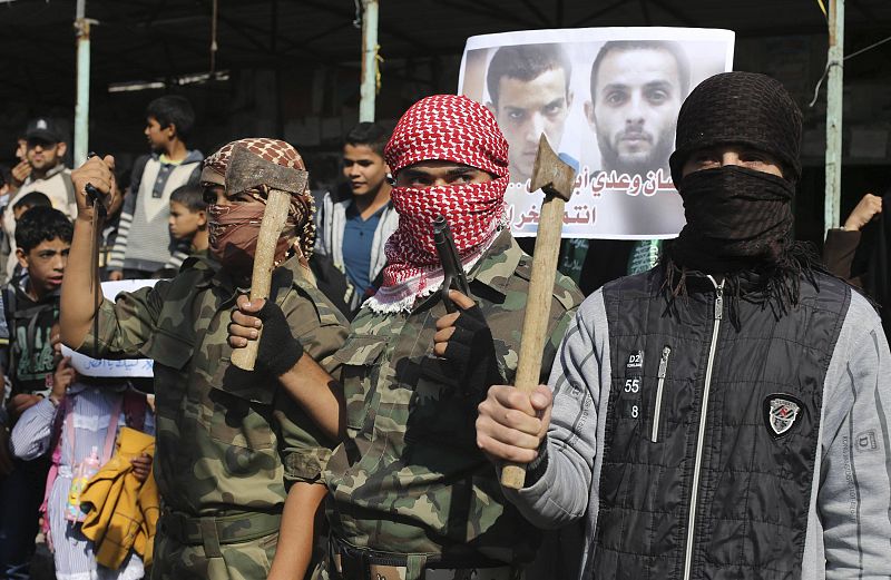Enmascarados portan hachas y rinden homenaje en Rafah a los dos autores del atentado (detrás, en la fotografía): Ghasan y Udai Abu Yamal