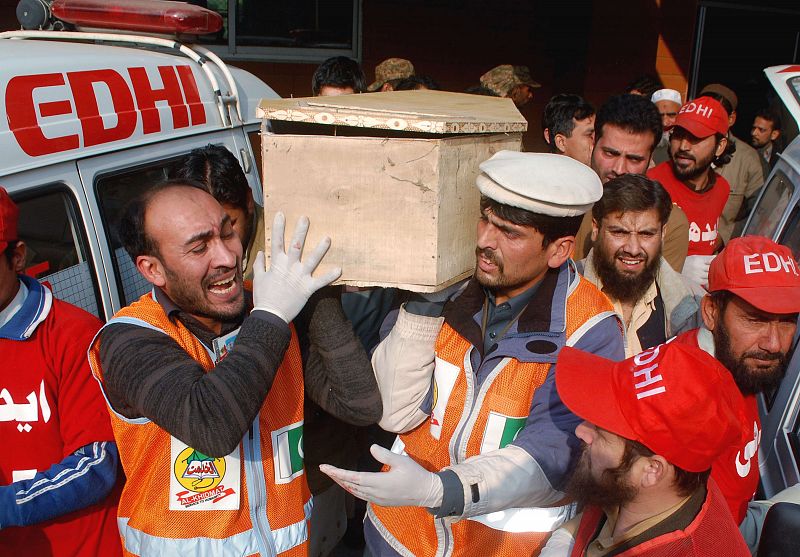 Trabajadores de los servicios de emergencias llevan el ataúd de una de las víctimas del asalto