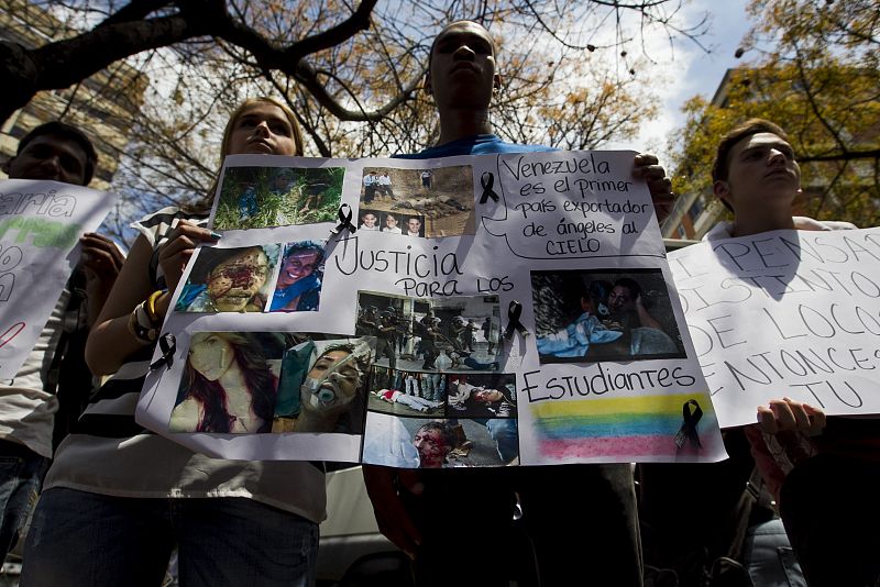 Un grupo de personas sostiene carteles durante la manfiestación por la muerte de un adolescente en Caracas