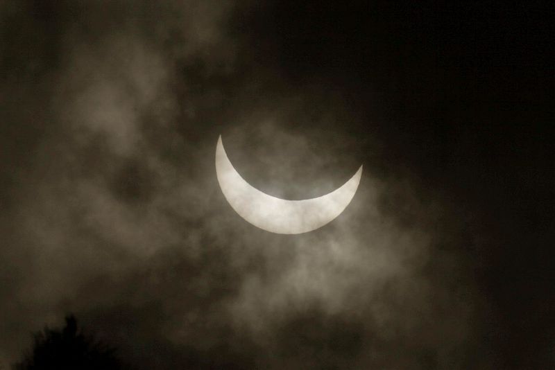 El eclipse de sol visto con dificultad debido a las nubes desde el parque de Santa Margarita de A Coruña, en Galicia, que es el mejor sitio para observar el fenómeno en la península.