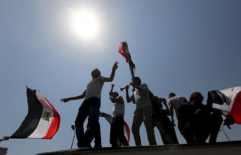 People cheer while carrying national flags in as they gather in Tahrir square to celebrate an extension of the Suez Canal