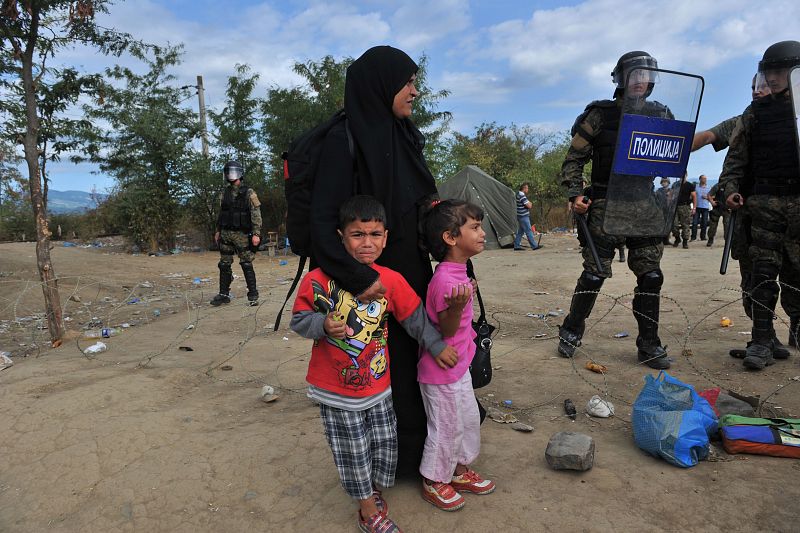 Una mujer y sus hijos esperan a pasar la frontera entre Grecia y Macedonia