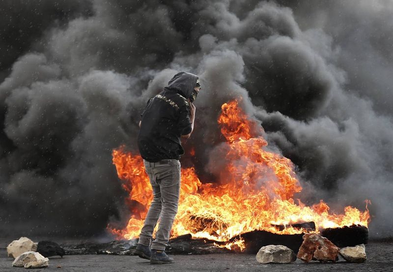 Un manifestante palestino frente a una hoguera de neumáticos ardiendo durente los enfrentamientos con las fuerzas de seguridad israelíes en Ramala