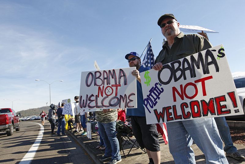 Un grupo de manifestantes recibe con mensajes de "Obama, no eres bienvenido" al presidente, que se reunió con las víctimas del tiroteo en Roseburg.