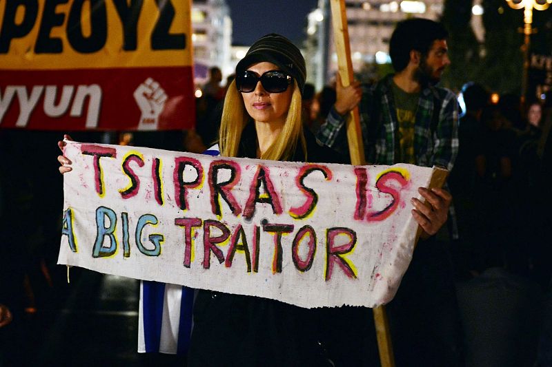 Una mujer sostiene una pancarta en la que puede leerse "Tsipras es un gran traidor" en una protesta ante el Parlamento contra el paquete de medidas aprobado.