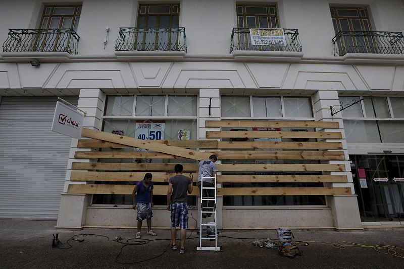 Varios empleados protegen las ventanas de su negocio en Puerto Vallarta, en el estado de Jalisco.