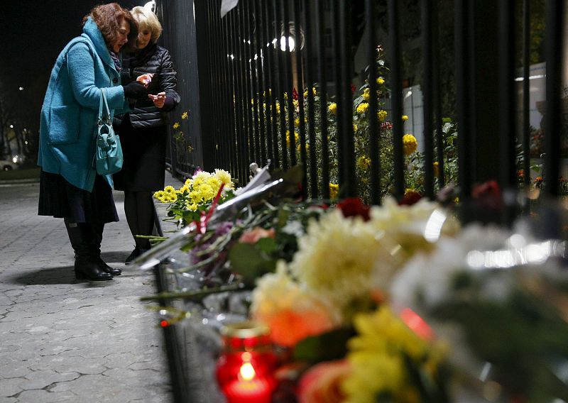 Unas mujeres encienden velas para recordar a las víctimas de la tragedia aérea en la embajada rusa en Kiev.