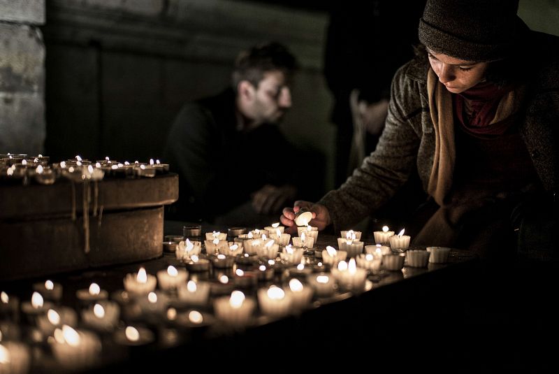 Una mujer enciende una vela a modo de tributo a las víctimas del ataque de París