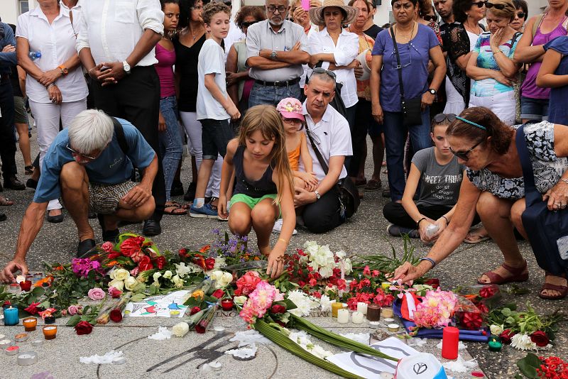 Un grupo de personas rinde homenaje con flores y velas en la plaza de los Derechos Humanos, en el distrito de Saint-Denis de la Reunion