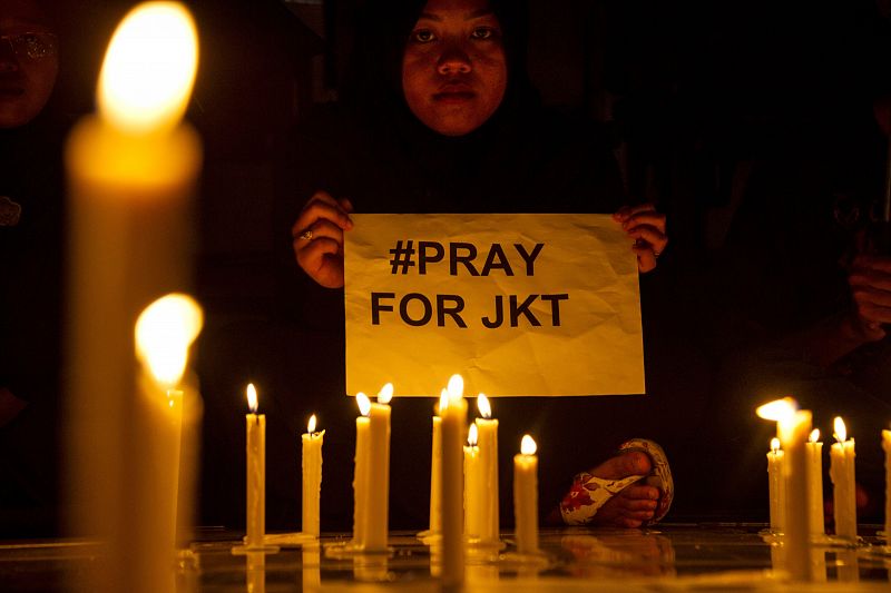 Una mujer sostiene un cártel que llama a rezar por Yakarta durante una vigilia tras los atentados