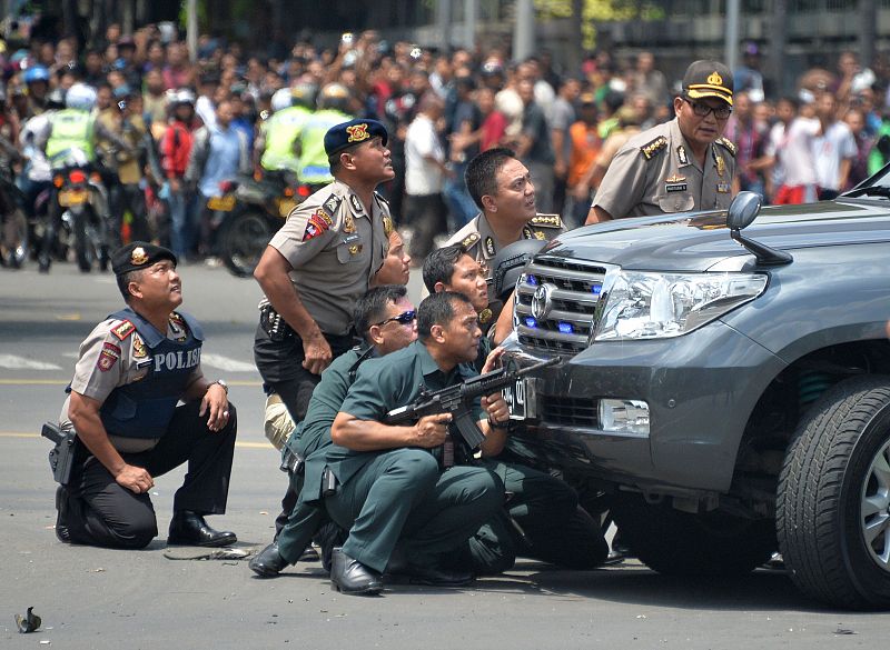 Un grupo de agentes de la policía indonesia toma posiciones durante el asalto contra los terroristas, frente al café que ha sufrido la primera explosión