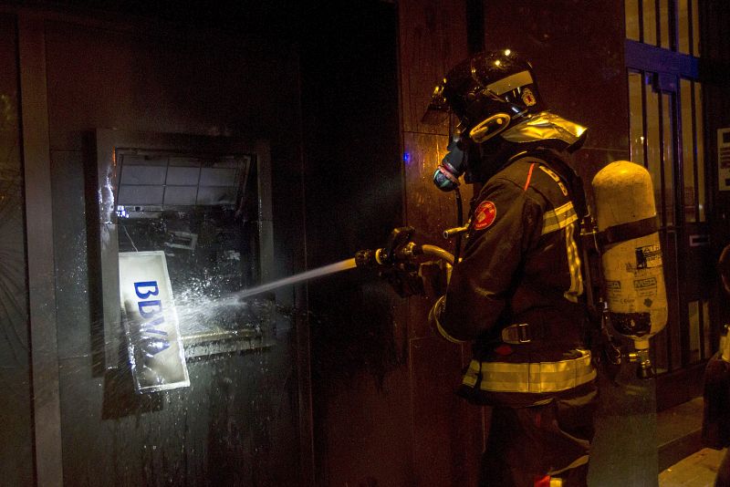 Un bombero apaga un cajero automático en la calle Gran de Gràcia.