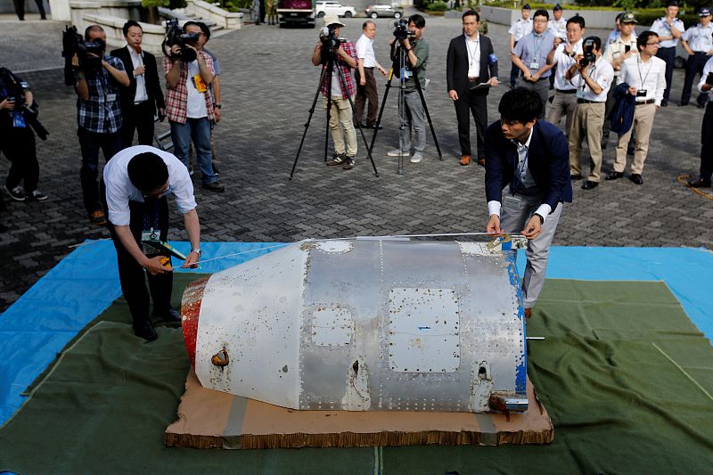 Officials of Defense Ministry check object, suspected to be half of nose cone from North Korean rocket launched in February, that washed up on Japanese beach, as it is shown to the media at the Defense Ministry in Tokyo