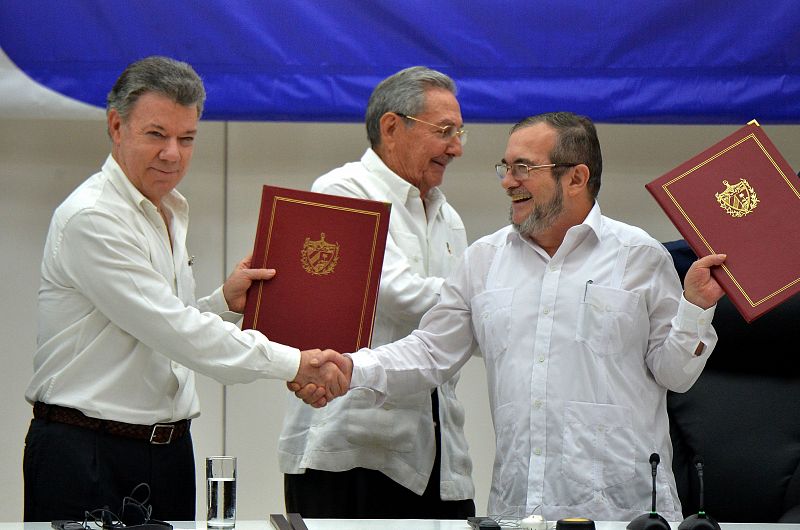 El presidente de Colombia y el líder de las FARC se dan la mano tras firmar el acuerdo.