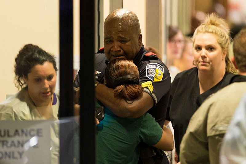 A DART police officer receives comfort at Baylor University Hospital emergency room entrance after a shooting attack in Dallas