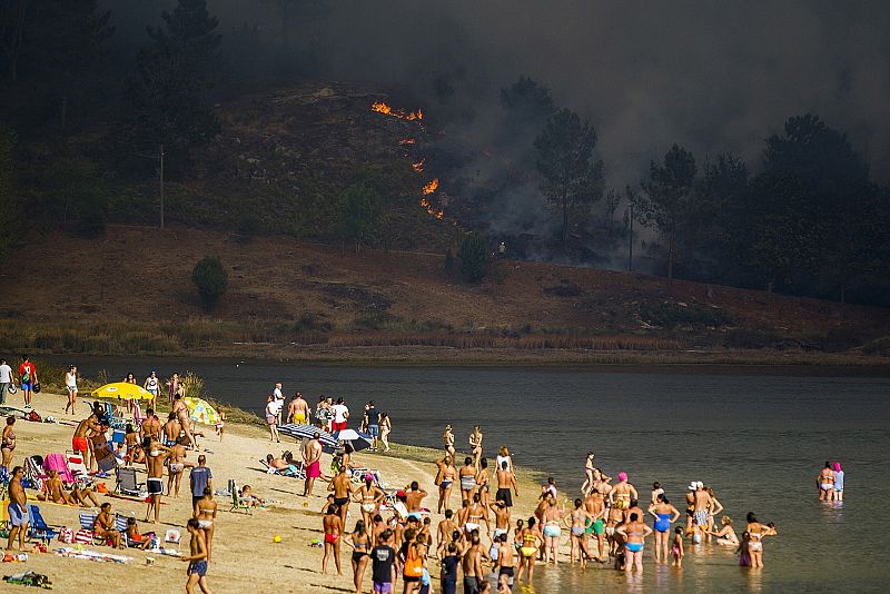 Turistas en la playa fluvial del río Verdugo observan el incendio forestal de Pontesampaio