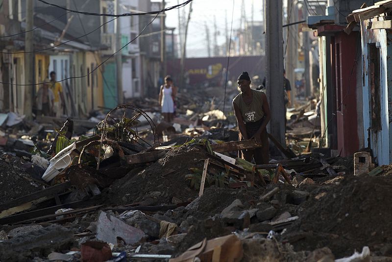 Un hombre limpia de escombros delante de su vivienda en Baracoa, Cuba