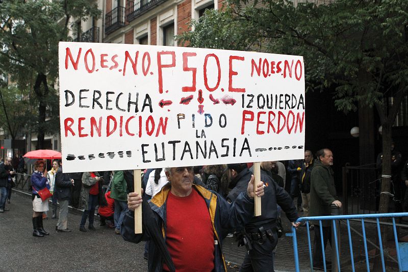 Una persona porta una pancarta ante la sede del PSOE