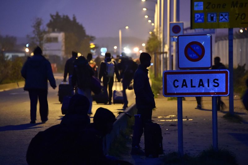 Migrantes junto al cartel de la localidad de Calais. Entre 6.000 y 8.000 migrantes, en su mayoría refugiados, van a ser reubicados.