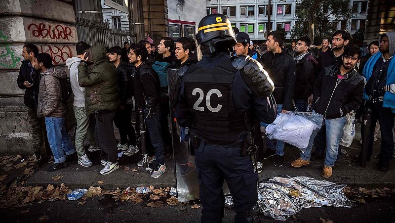Policías antidisturbios ante una fila de migrantes cerca de las estaciones de metro de Jaures y Estalingrado, en París.