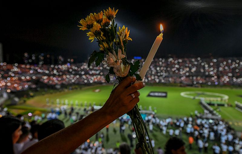 Una aficionada porta una vela y un ramo de flores en honor a las víctimas del Chapecoense.