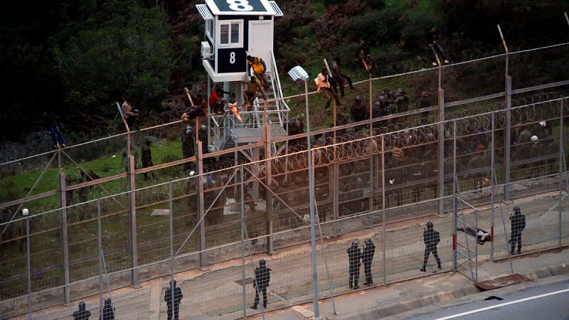 Inmigrantes subsaharianos encaramados en lo alto de la valla de Ceuta, este viernes