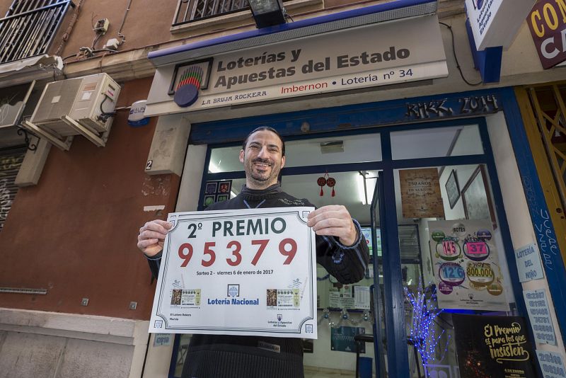 El gerente de la administración de loterias La Bruja Rockera, la número 34 de Murcia, muestra el cartel del 95.379, segundo premio del sorteo del niño, dotado con 75.000 euros.