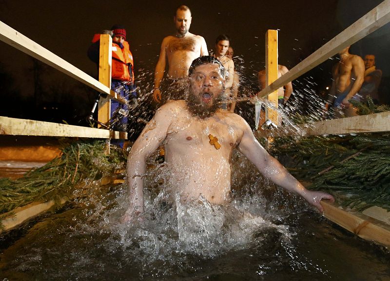 Man takes dip in ice hole in pond near Church of Saint Euphrosyne during Orthodox Epiphany celebrations in Moscow