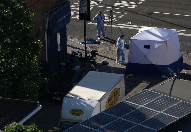 La Policía examina la furgoneta (a la izquierda, con un logotipo amarillo) con la que un nombre ha atropellado a numerosas personas en el norte de Londres. La Policía asegura que el suceso tiene todas las características de un "atentado terrorista".