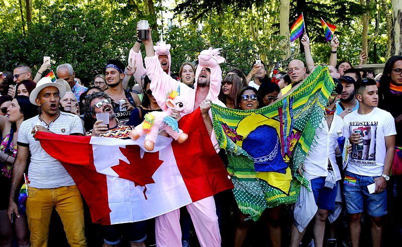 Asistentes a la marcha del 'Orgullo' 2017 en Madrid portando banderas de Canadá y Brasil