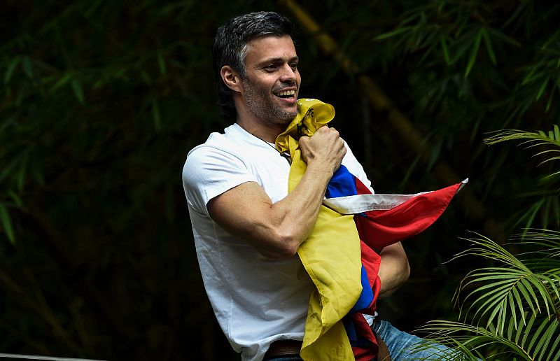 López sostiene la bandera de Venezuela mientras saluda a sus seguidores