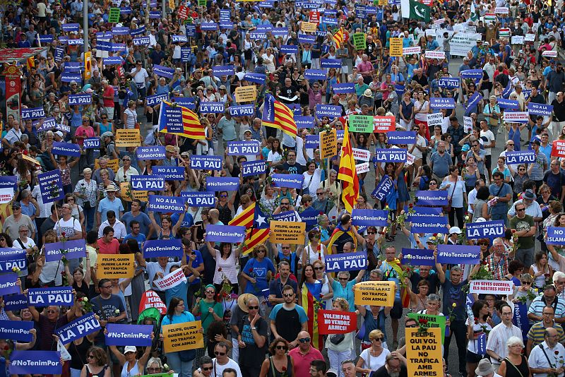 Numerosas personas sostienen el cartel con la frase "La millor resposta ès la pau" (La mejor respuesta es la paz) durante la marcha contra el terrorismo en Barcelona.